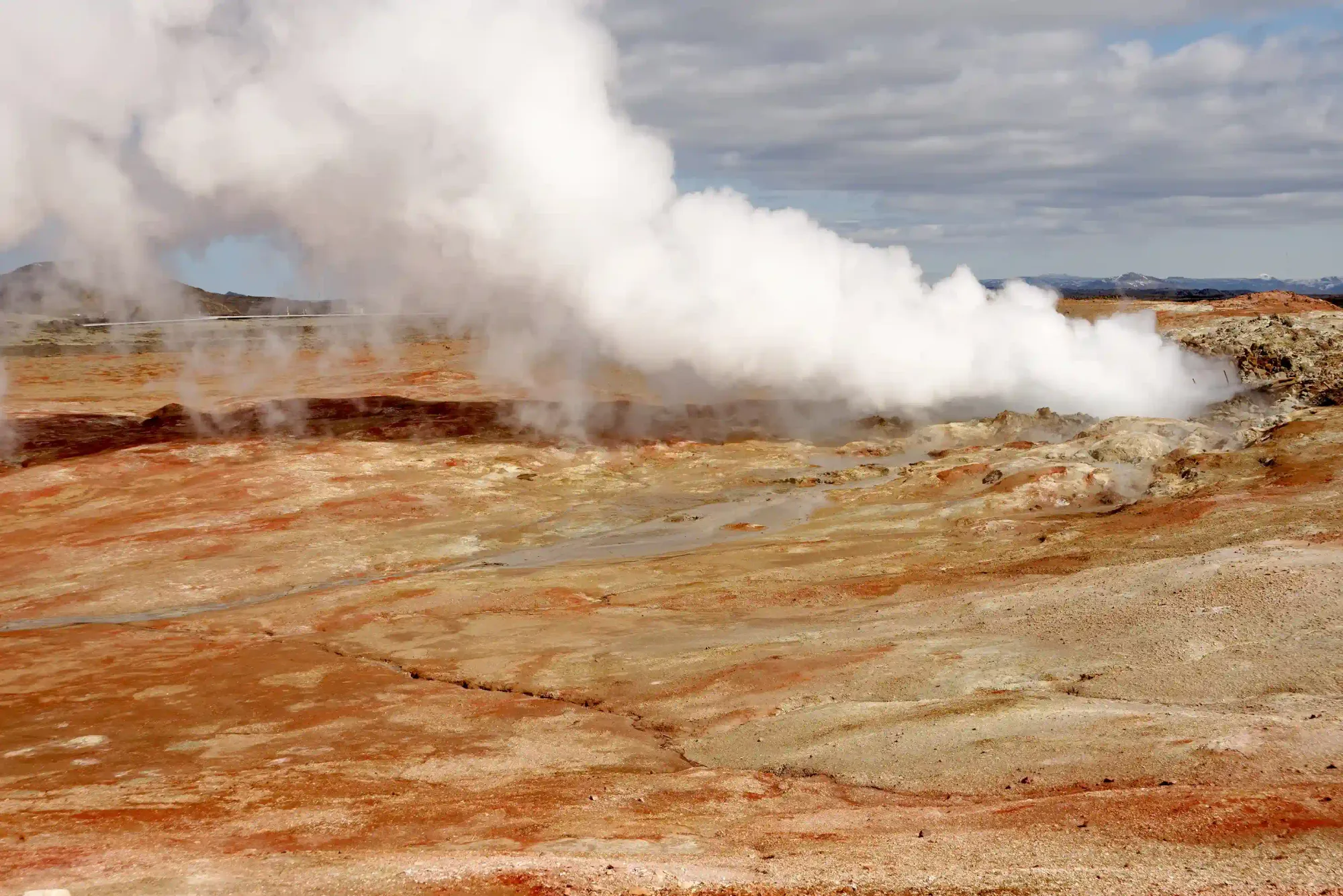 Gunnuhver boiling mud pool with dense white steam rising above dark volcanic terrain, southwest Reykjanes Peninsula